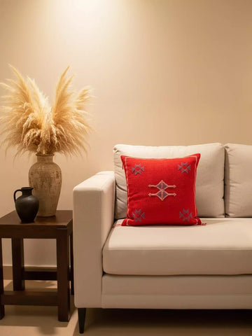 Moroccan red wool pillow on beige sofa with rustic pottery and pampas décor