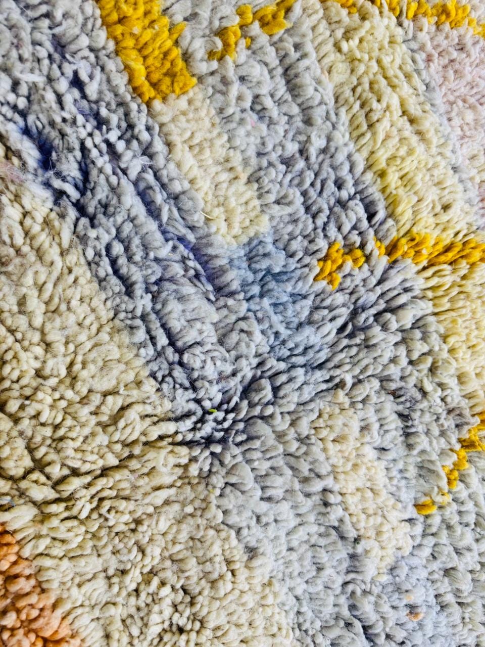 Close-up of cream and gray Berber wool texture with yellow accents.