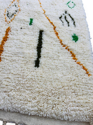 Close-up of cream Moroccan wool rug with green and mustard geometric details