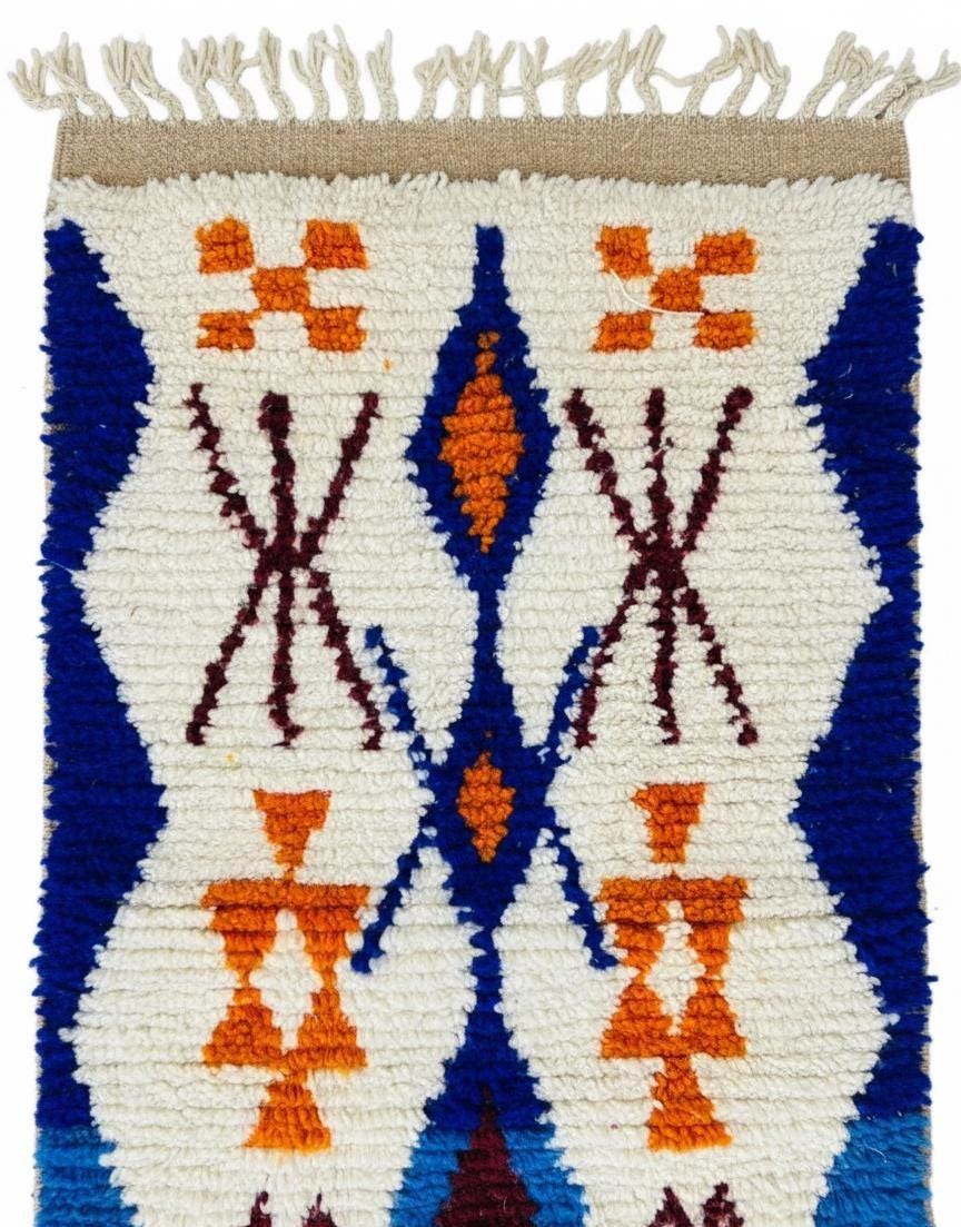 Handwoven Moroccan runner rug featuring bold blue waves and orange tribal motifs on an ivory base with tasseled fringe.