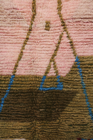 Detail of Moroccan rug center design featuring pink abstract form outlined with olive green and blue lines