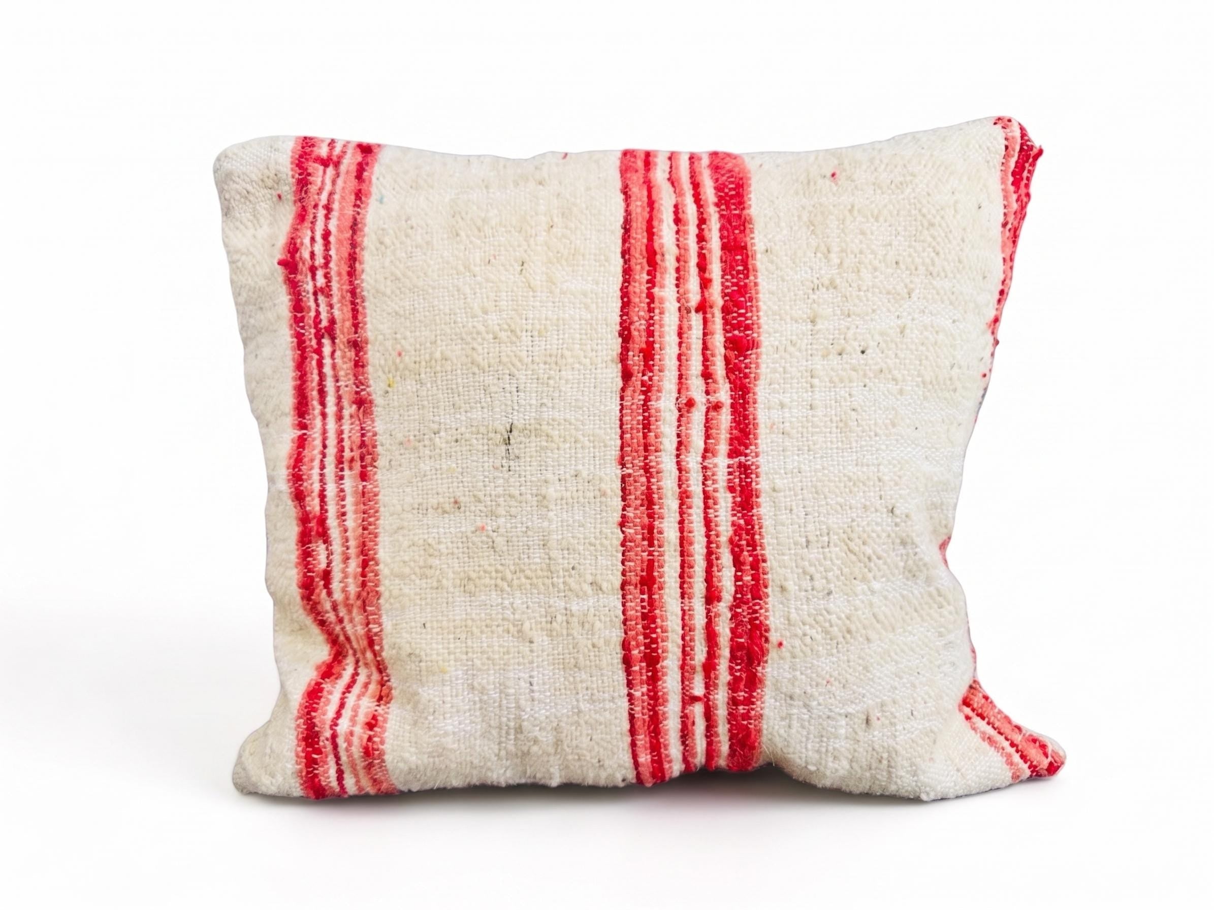 Handmade red stripe Moroccan wool throw pillow isolated on a white background.