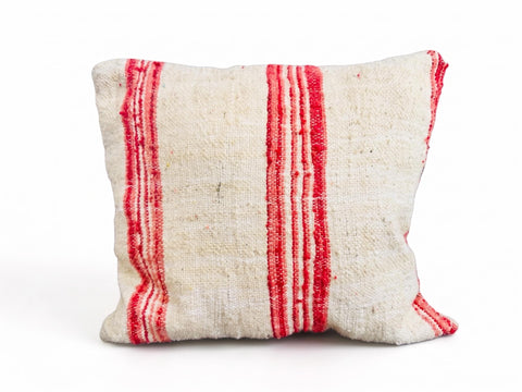 Handmade red stripe Moroccan wool throw pillow isolated on a white background.