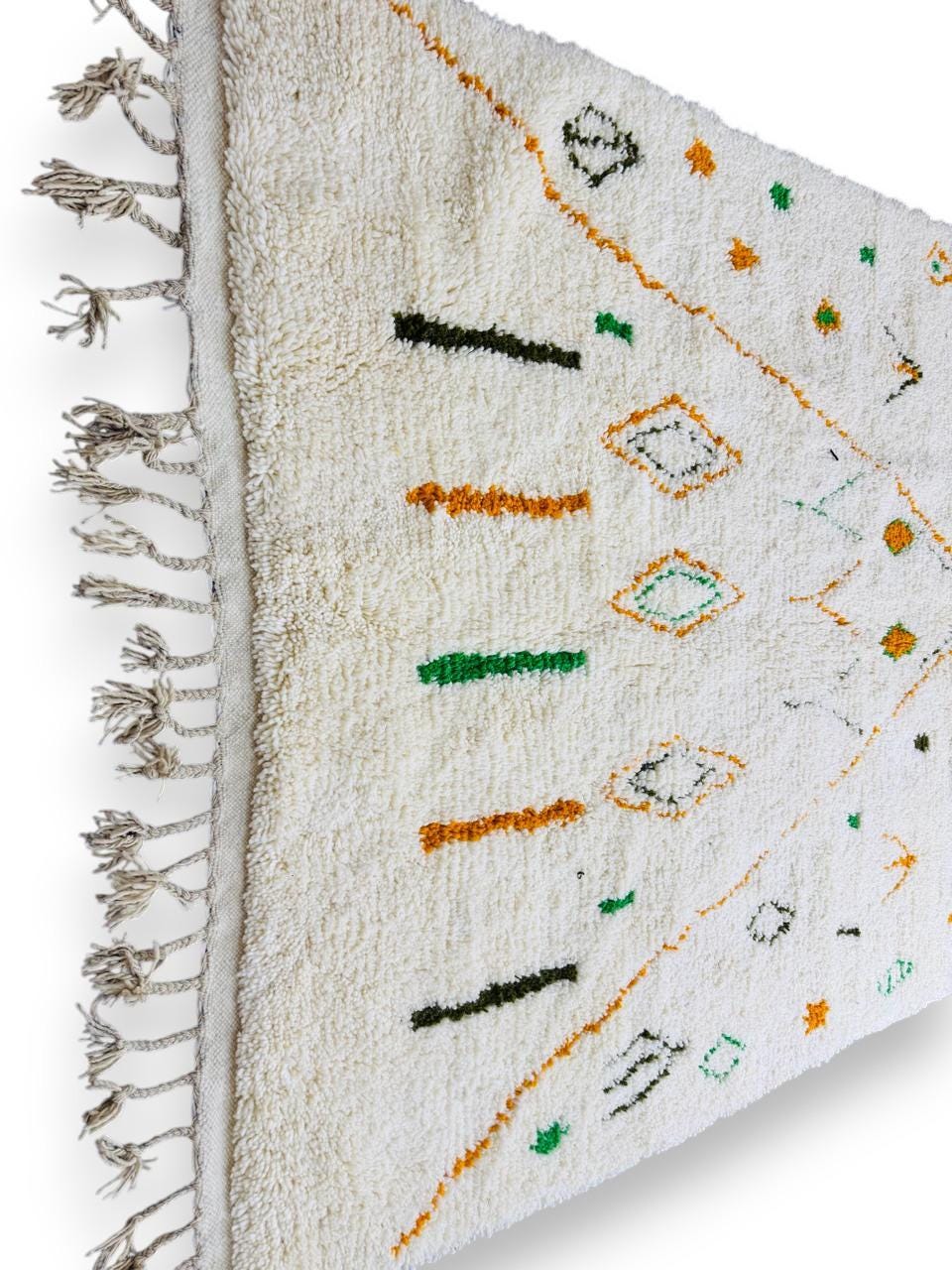 Moroccan Berber rug displayed hanging with tassel fringe detail