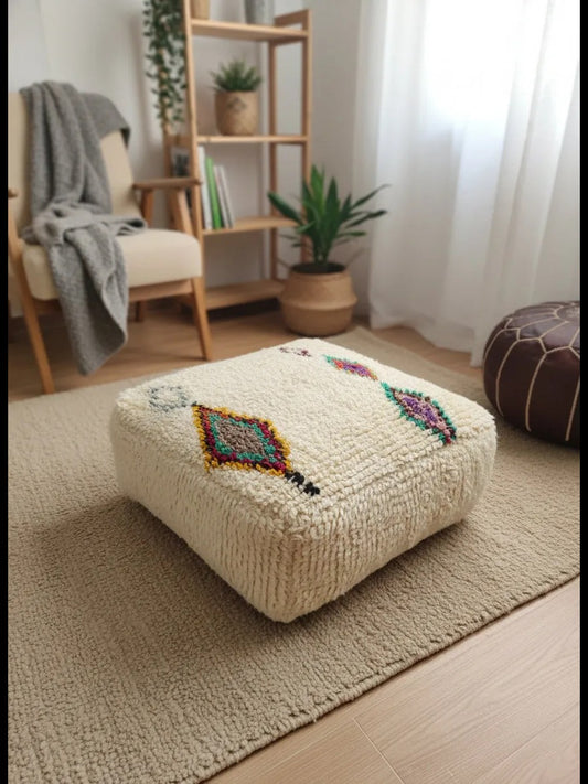 Cream Amnay Berber pouf on a beige rug.