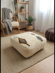 Cream Amnay Berber pouf on a beige rug.