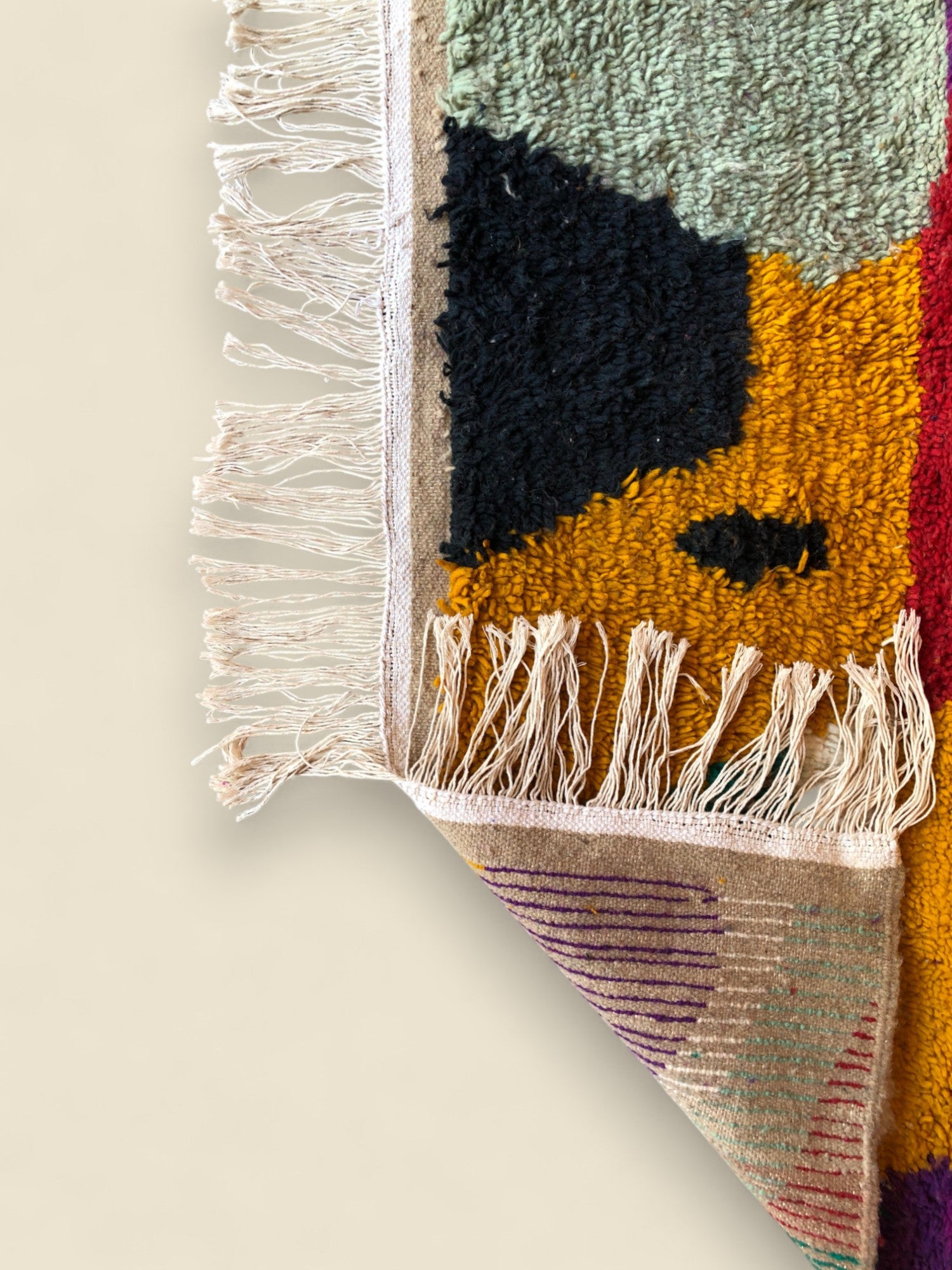 Edge view of multicolored Moroccan wool rug showing fringe and woven detail