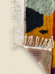 Edge view of multicolored Moroccan wool rug showing fringe and woven detail
