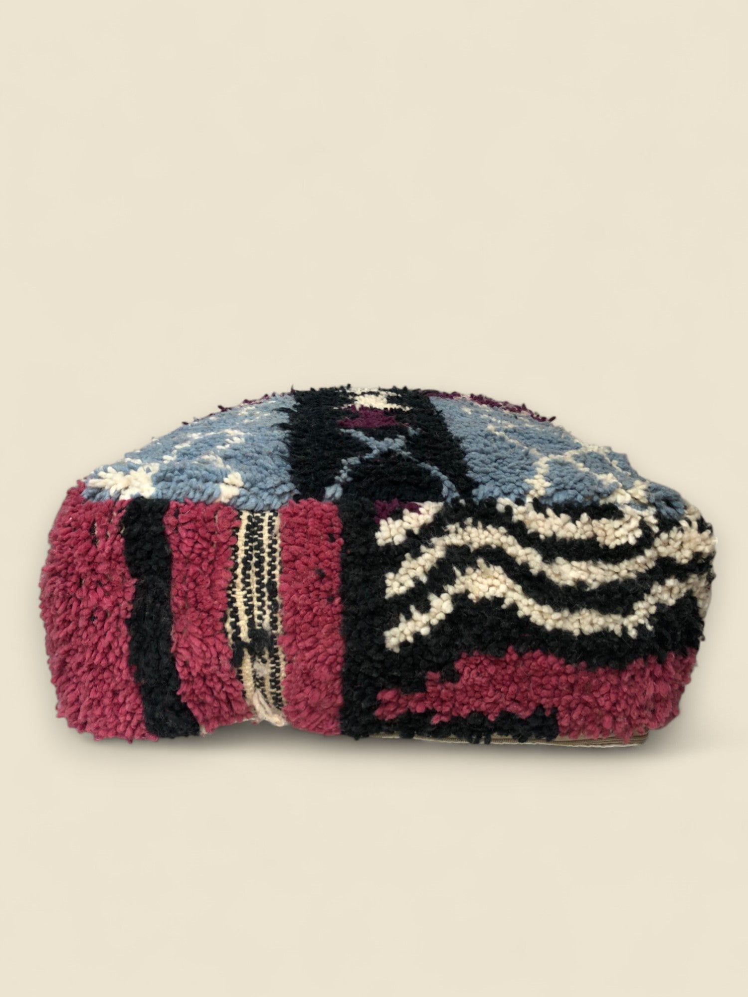 Colorful Moroccan pouffe with geometric motifs in blue, burgundy, and ivory wool