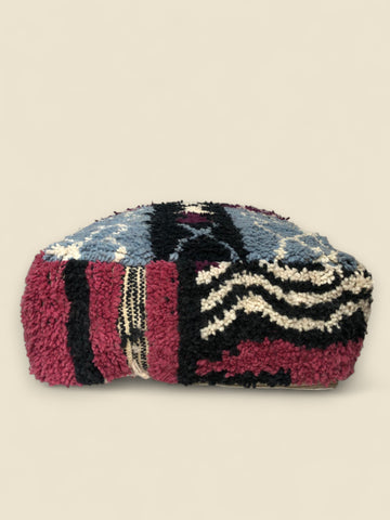 Colorful Moroccan pouffe with geometric motifs in blue, burgundy, and ivory wool