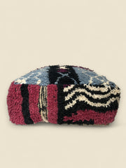 Colorful Moroccan pouffe with geometric motifs in blue, burgundy, and ivory wool