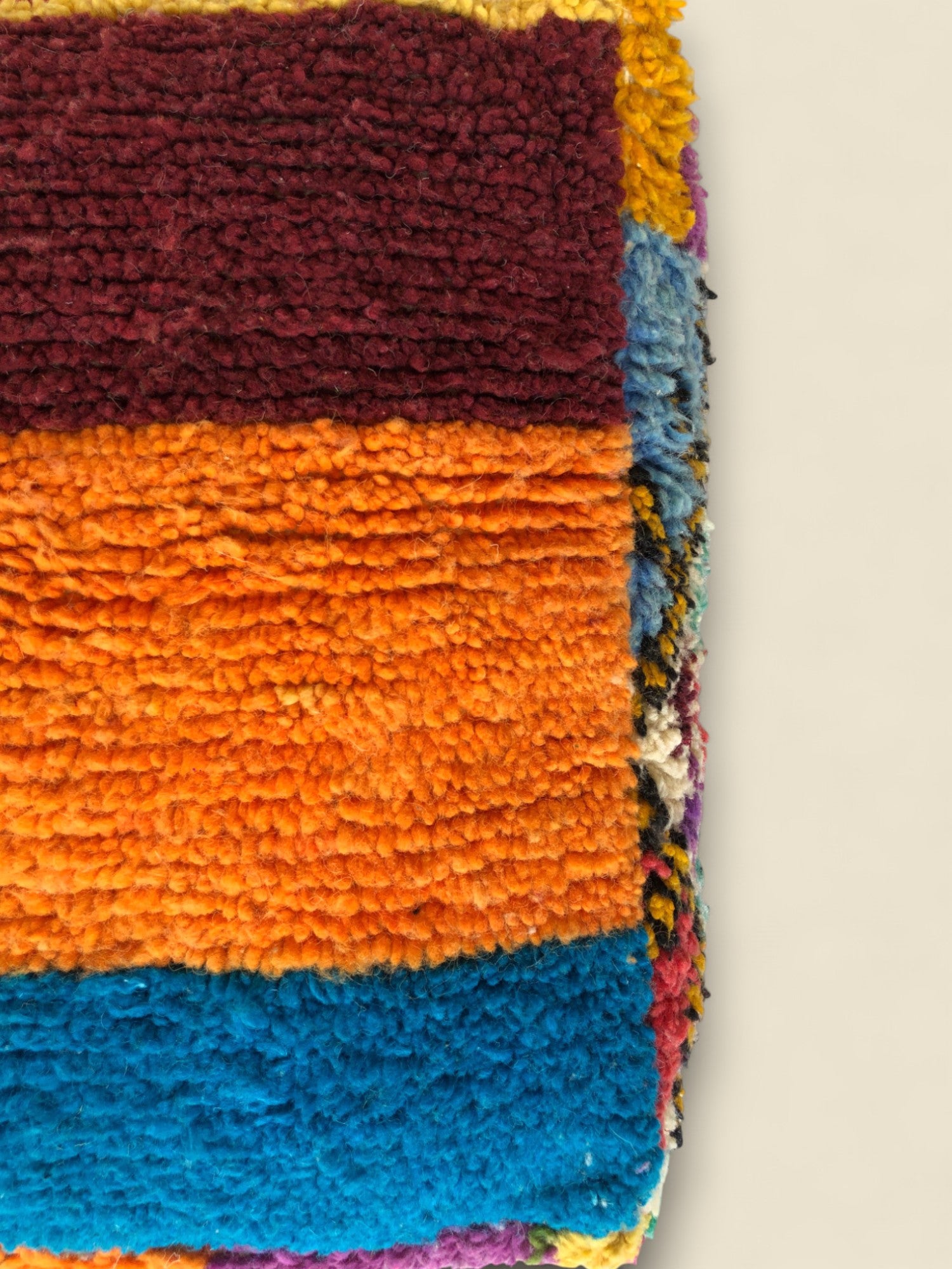Detailed close-up of pouffe texture featuring thick orange and blue wool