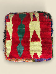 Top view of the Awrar Moroccan pouffe featuring bold red background and geometric Berber patterns.
