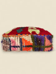 Side view of the Awrar pouffe showing colorful handwoven patchwork in purple, orange, and cream tones