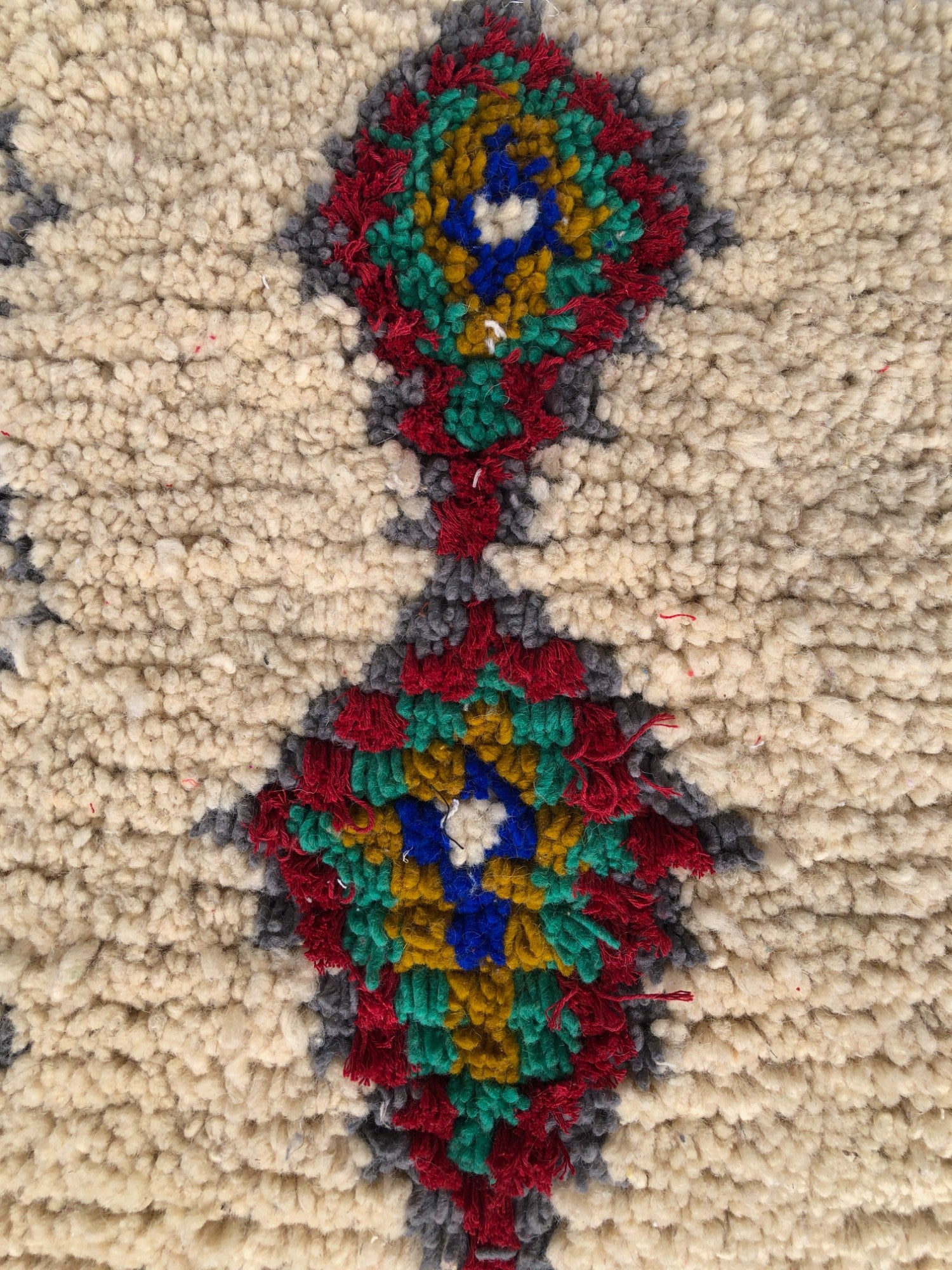 Close-up of traditional Berber diamond design in red, green, mustard, and blue wool