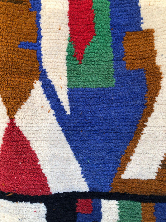 Close-up of Amayas Moroccan rug showing abstract handwoven wool pattern in blue, green, red, and ochre.