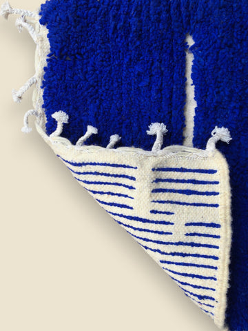 Blue and white textured rug with tassels on a beige background