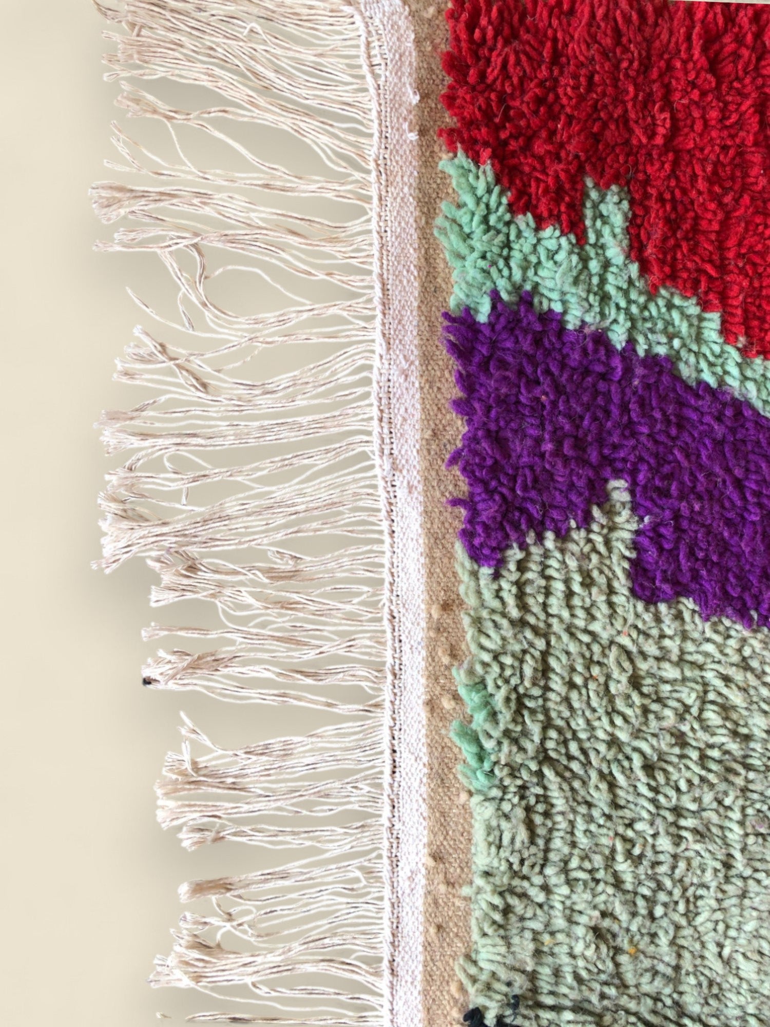 Edge view of multicolored Moroccan wool rug showing fringe and woven detail