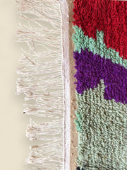 Edge view of multicolored Moroccan wool rug showing fringe and woven detail