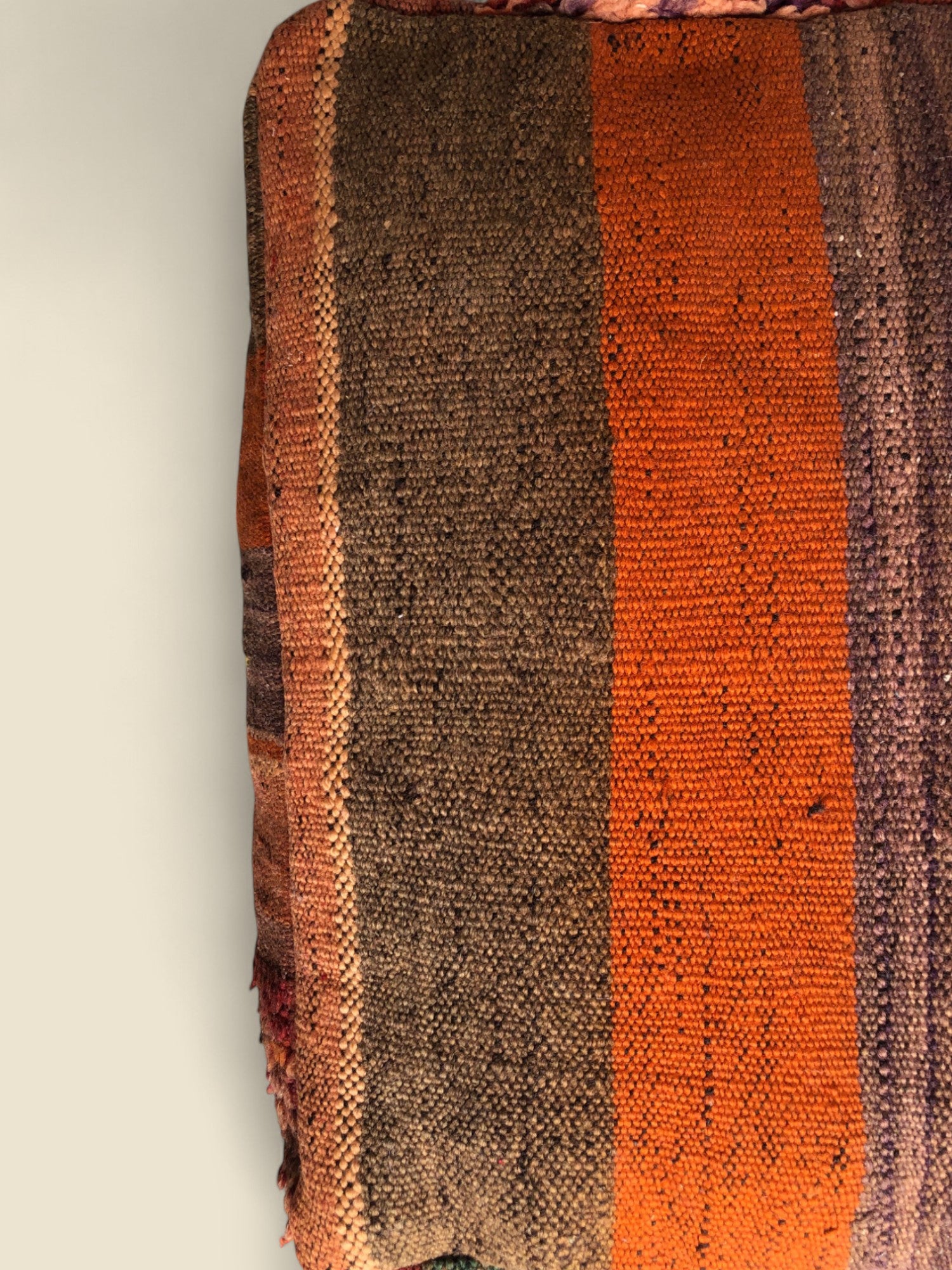 Woven green, orange, and brown kilim pattern on side of pouffe