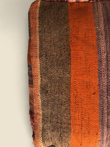 Woven green, orange, and brown kilim pattern on side of pouffe