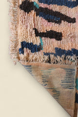 Handwoven Hafna Moroccan rug with abstract Berber designs in teal, indigo, and blush on a warm wool base.