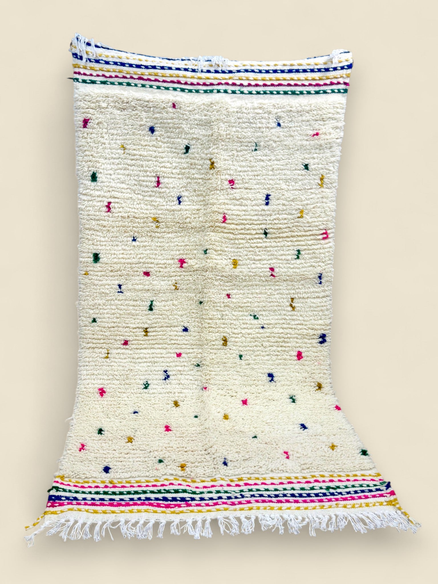 Ivory Berber rug with rainbow stripes and hand-knotted fringe.