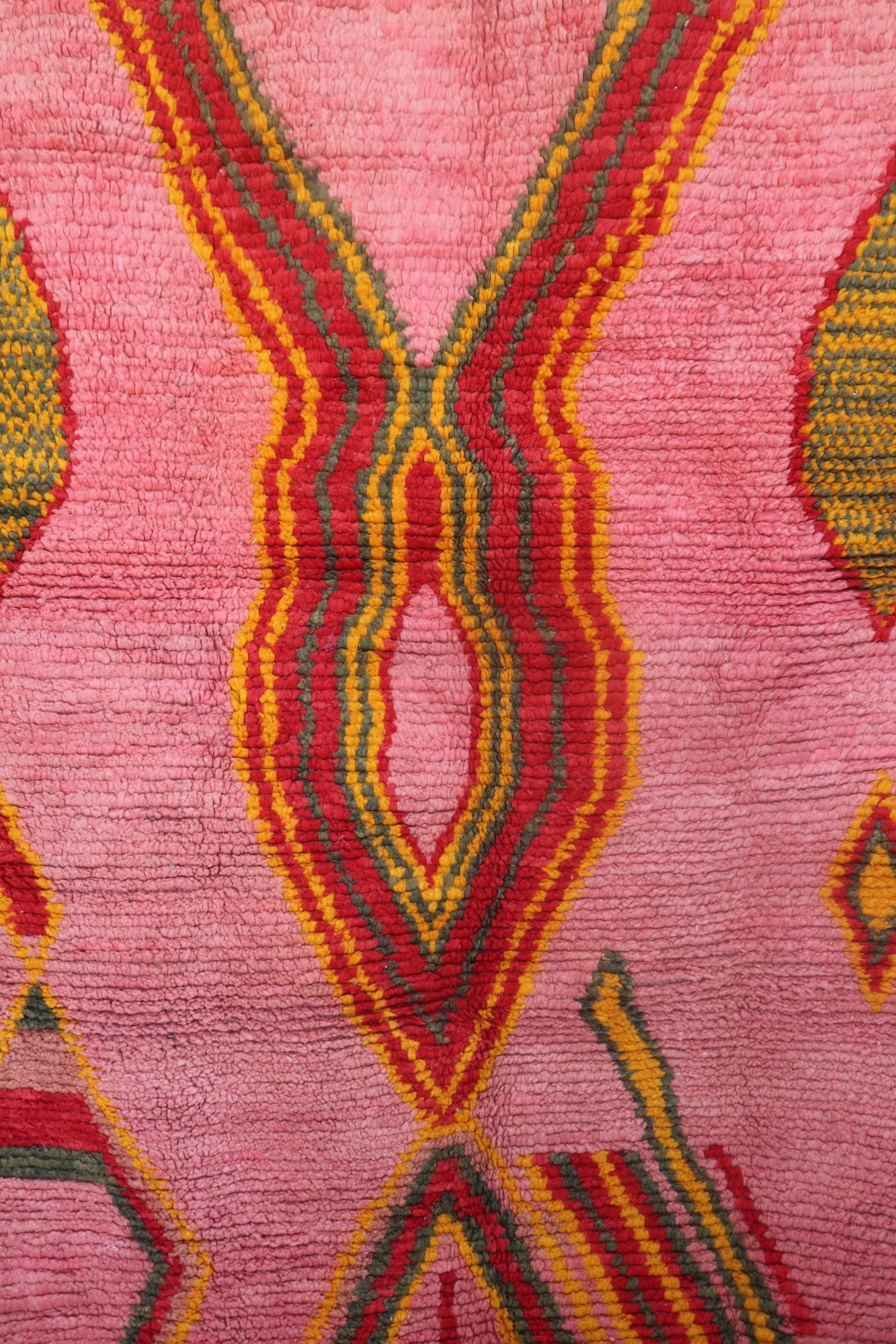 Central diamond pattern of the Limra rug in red, mustard, and olive green