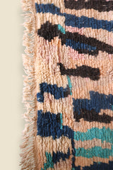 Bottom corner of the Hafna Moroccan rug with fringe and layered brushstroke-style patterns.
