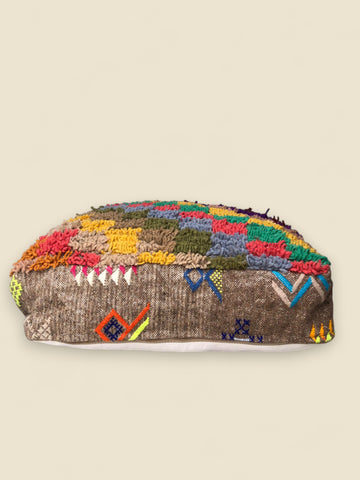 Side view of pouffe showing tribal embroidery on flatwoven brown wool