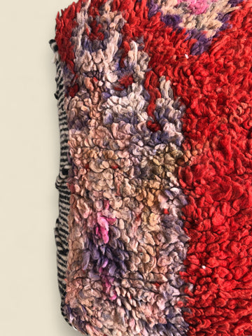 Detailed close-up of the corner showing vibrant red wool and faded pastel hues in thick shag.