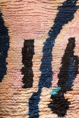 Vibrant lower details of the Hafna rug with black, indigo, and turquoise accents on a peachy base.