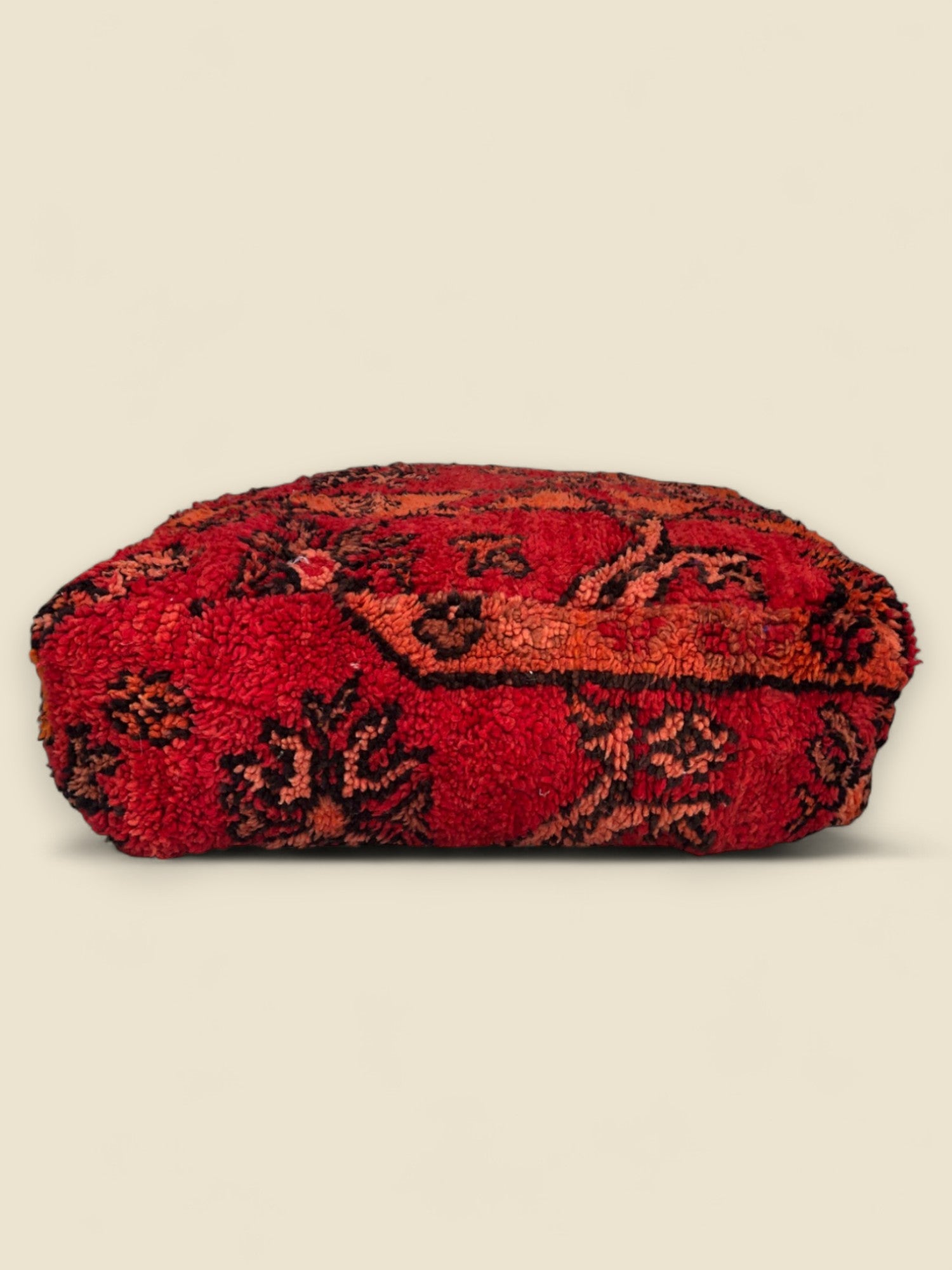 Side view of vintage Moroccan wool pouffe in deep red tones