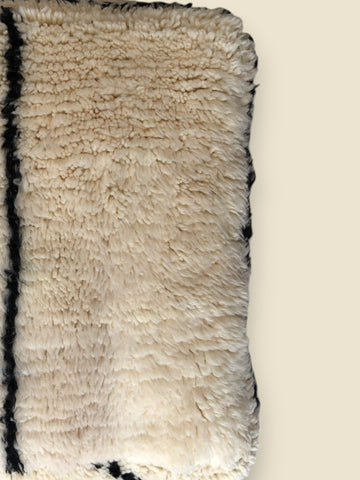 Close-up of Amilu pouffe showing textured wool and simple pattern.