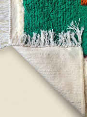Reverse side of a Moroccan rug with fringed edge and green wool surface