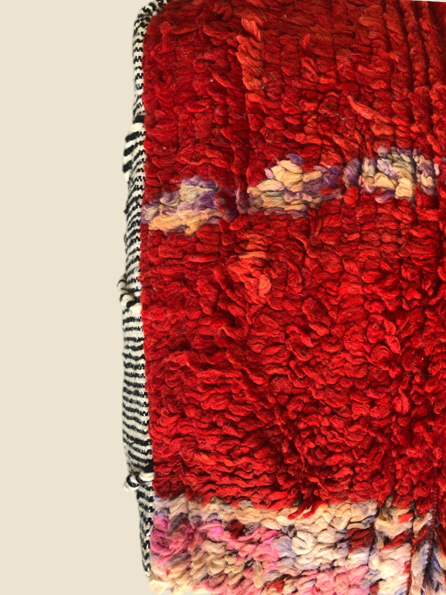 Handmade Taghraft Moroccan pouffe with red shaggy wool top and tribal motifs in black, white. 