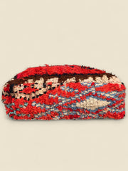 Side view of colorful Moroccan Boujad wool pouffe in red, turquoise, and brown tones