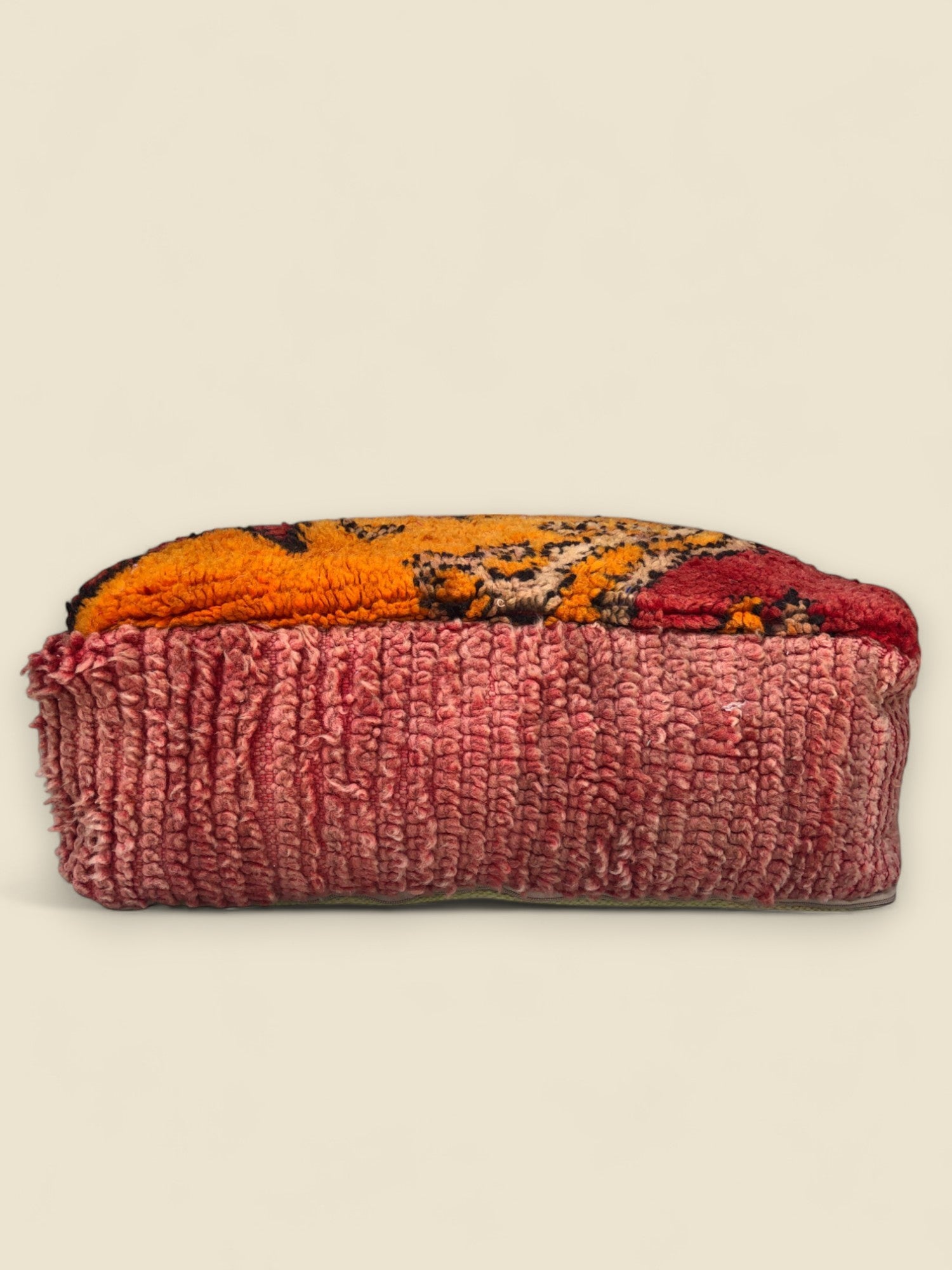 Side view of Tamghart Moroccan pouffe made from vintage red and orange Berber wool