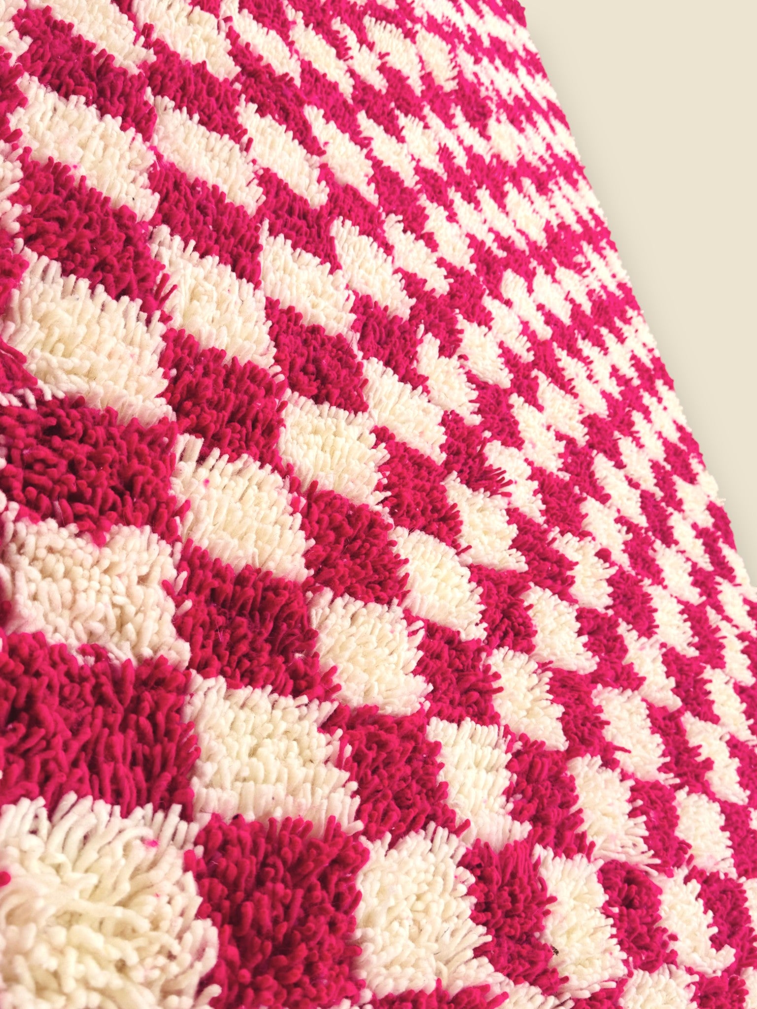 Detailed side view of pink and white wool checkerboard rug texture