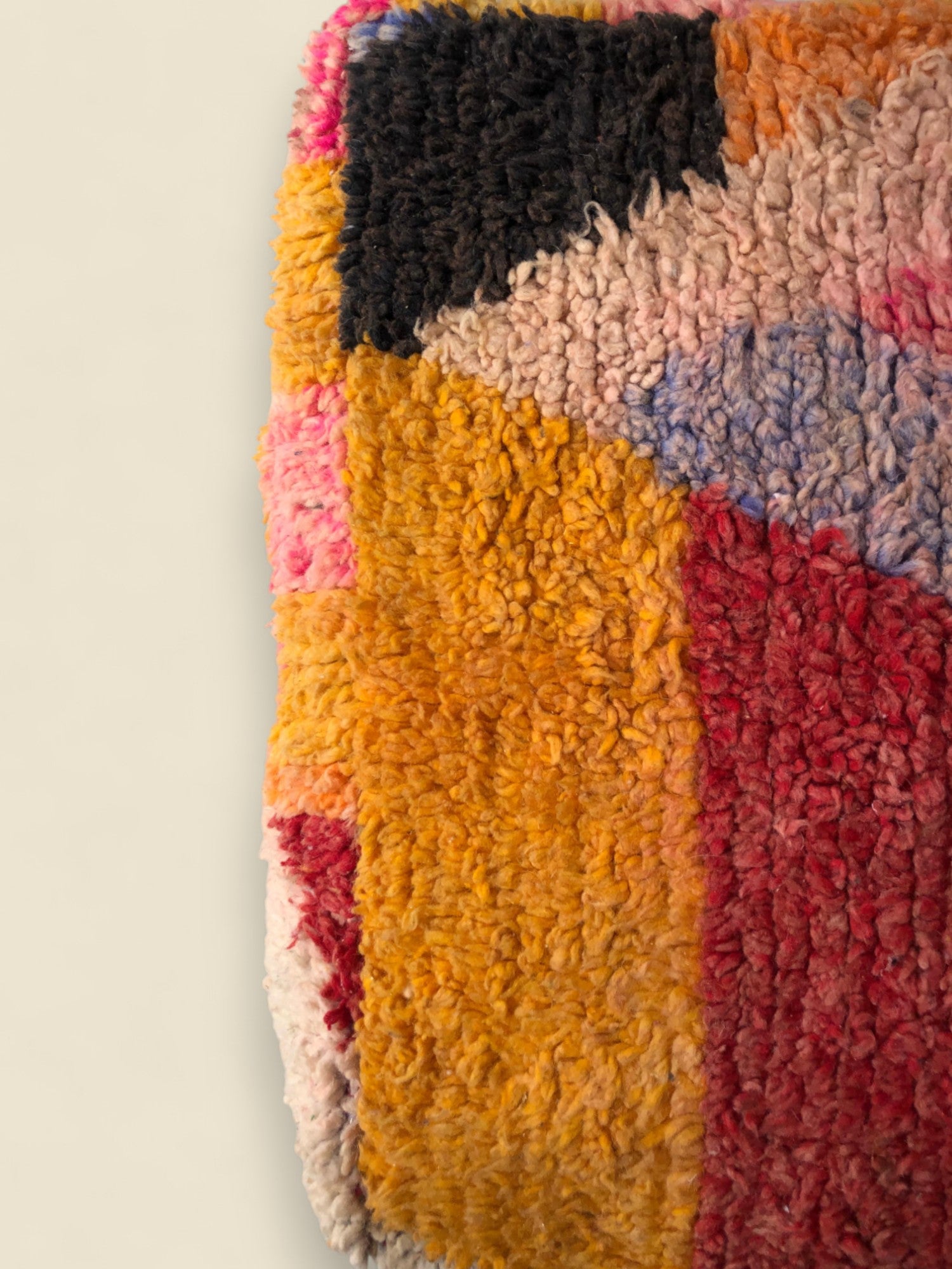 Close-up of Tawenza pouffe corner with dark wool patch and yellow section