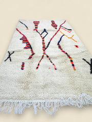 Cream Moroccan rug with abstract design and fringed edges.