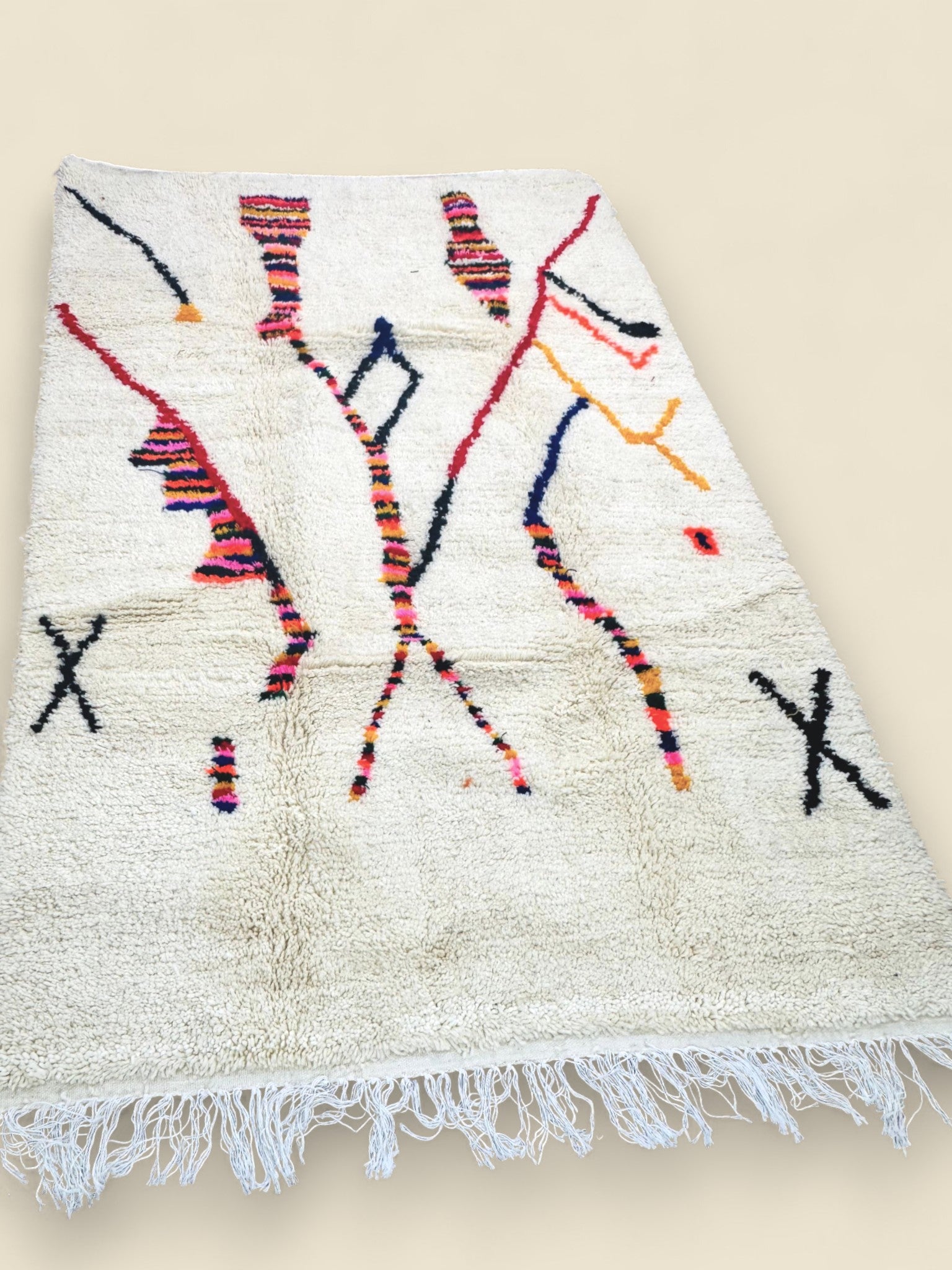 Moroccan wool rug with colorful patterns laid flat on a wooden floor.