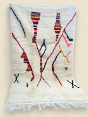 Full view of the Tazla rug showing multicolored lines and cream wool texture.