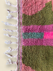  Close-up of Tazult Moroccan Rug showing pink and green wool texture with braided fringe