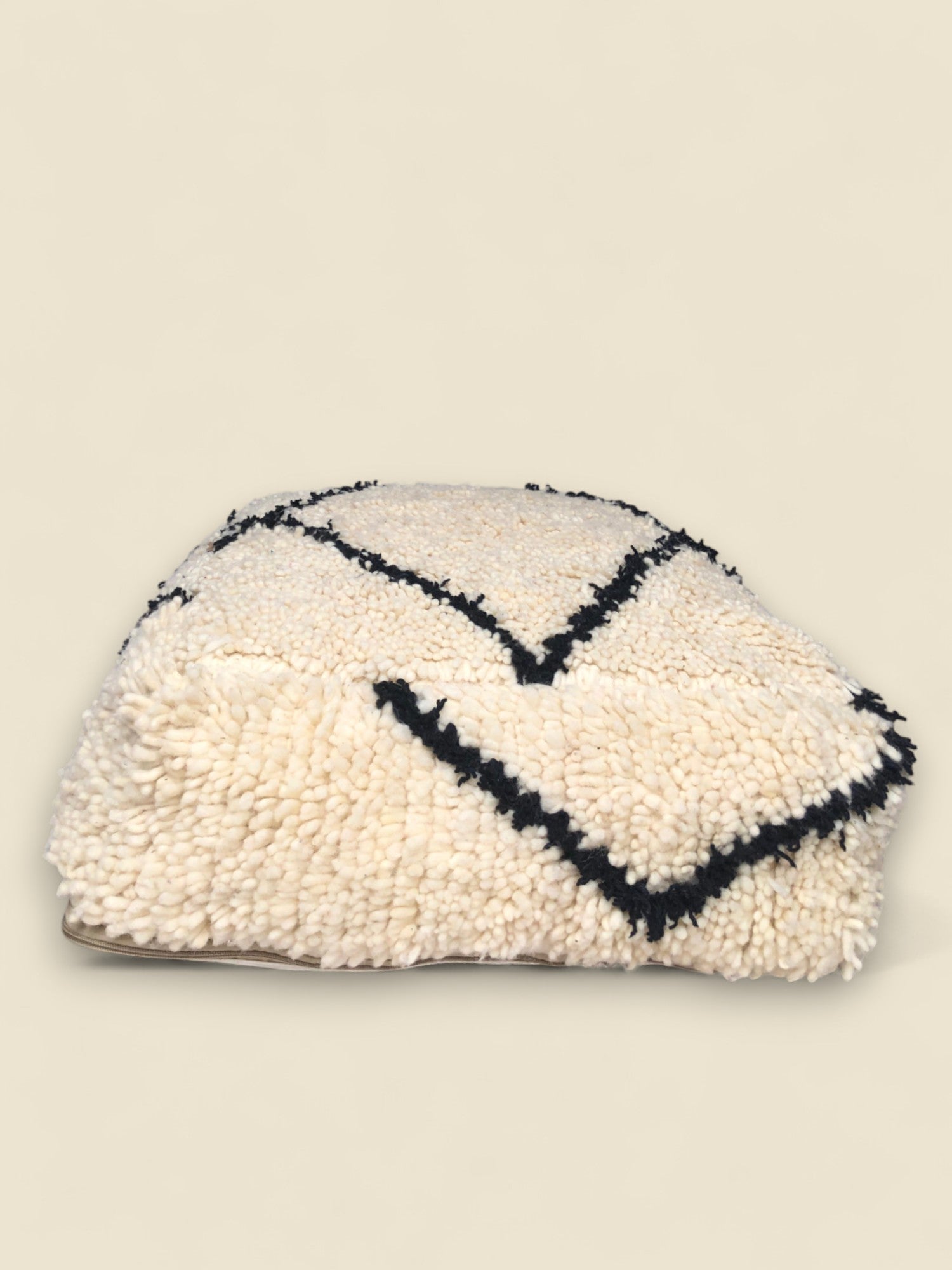 Side view of Thimlilt pouffe showing its low-profile cushioned form