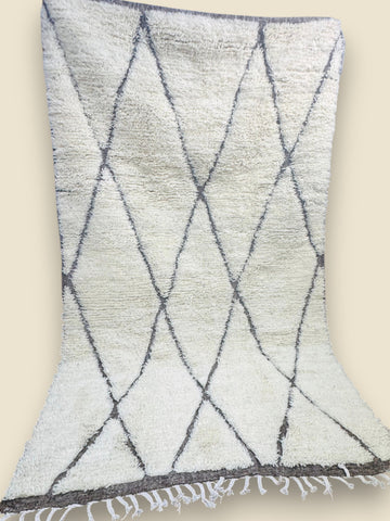 Moroccan handmade rug with fringed ends displayed on wooden floor