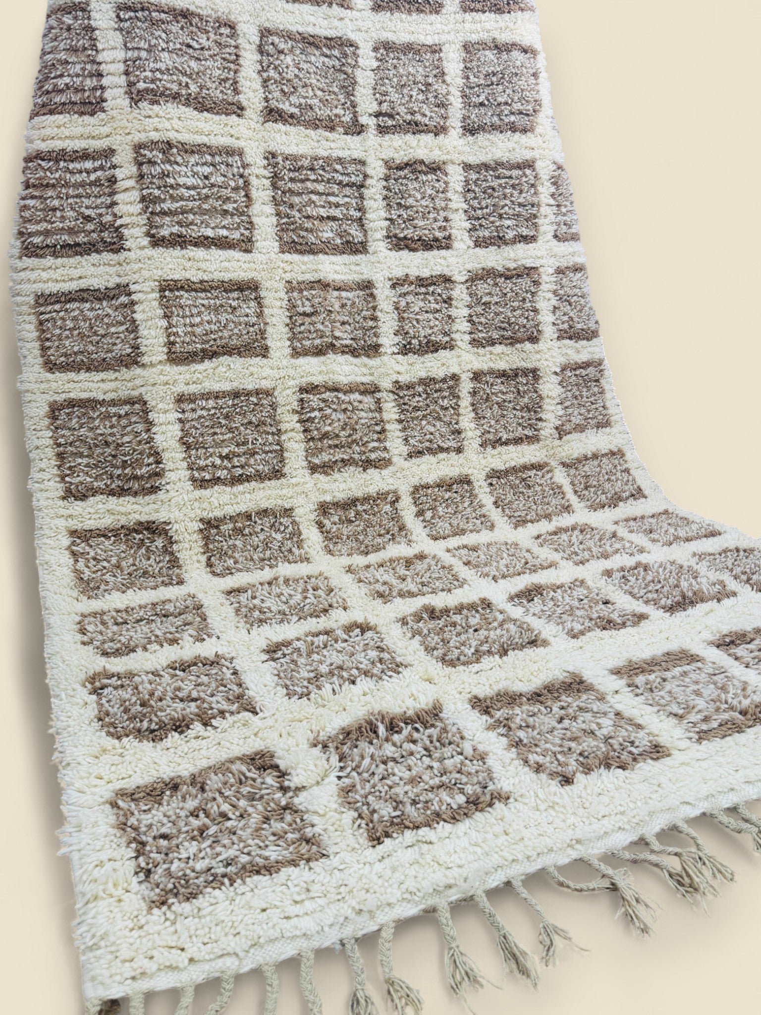 Side angle of Tilila rug showing checkered design and tassel fringes