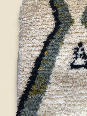 Close-up of textured wool surface with olive and black zigzag embroidery
