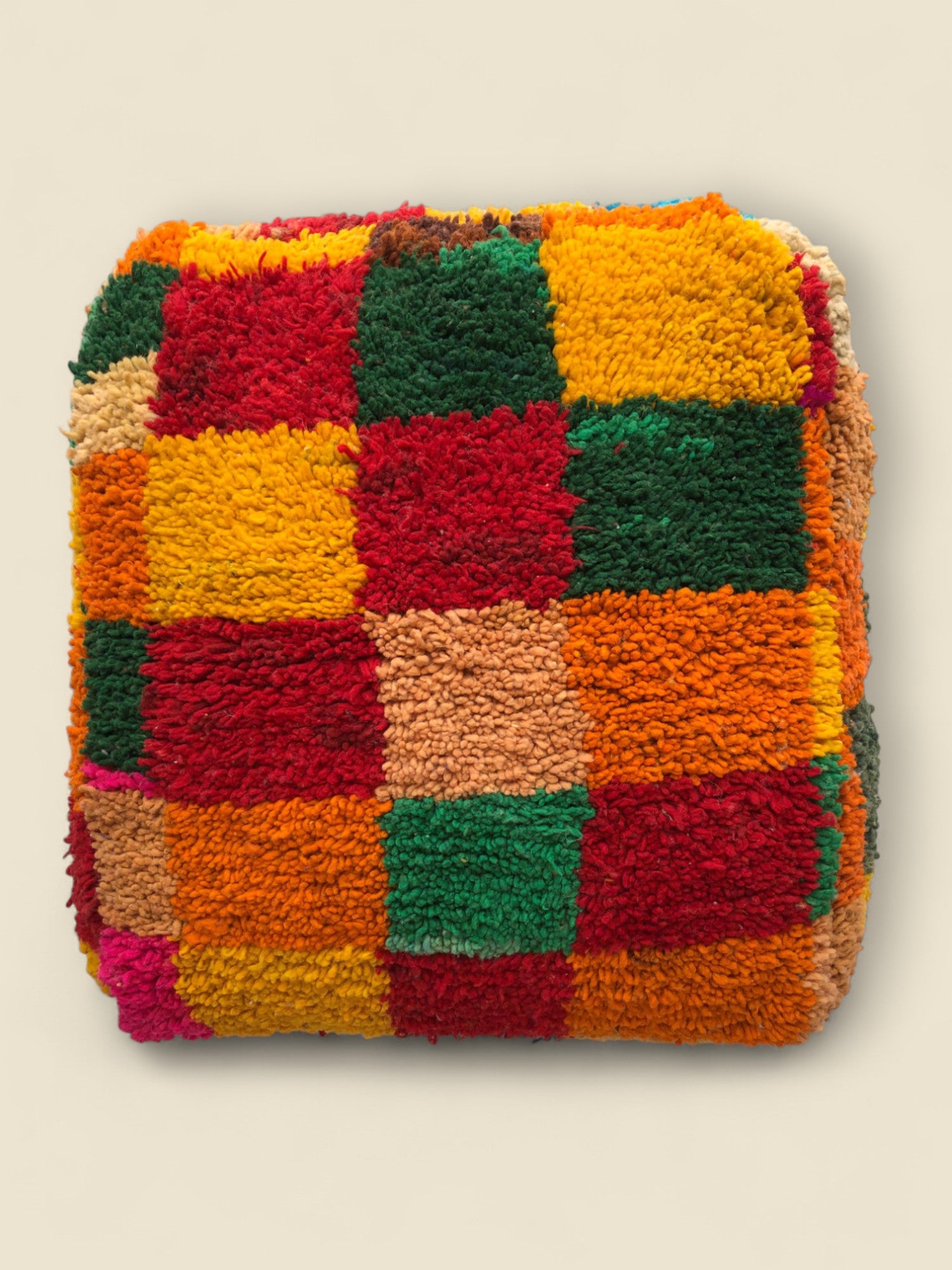 Top view of handmade Tirga Moroccan pouffe with bold multicolor checkerboard design