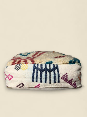 Side view of the Tizerzit Moroccan pouffe featuring bold navy, yellow, and pink Berber motifs